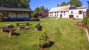 Een binnentuin met picknicktafels, een kleine tuin en een gebouw met een witte gevel en schuin dak.