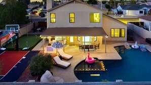 Una casa moderna con piscina, mobiliario de exterior y cancha de baloncesto.