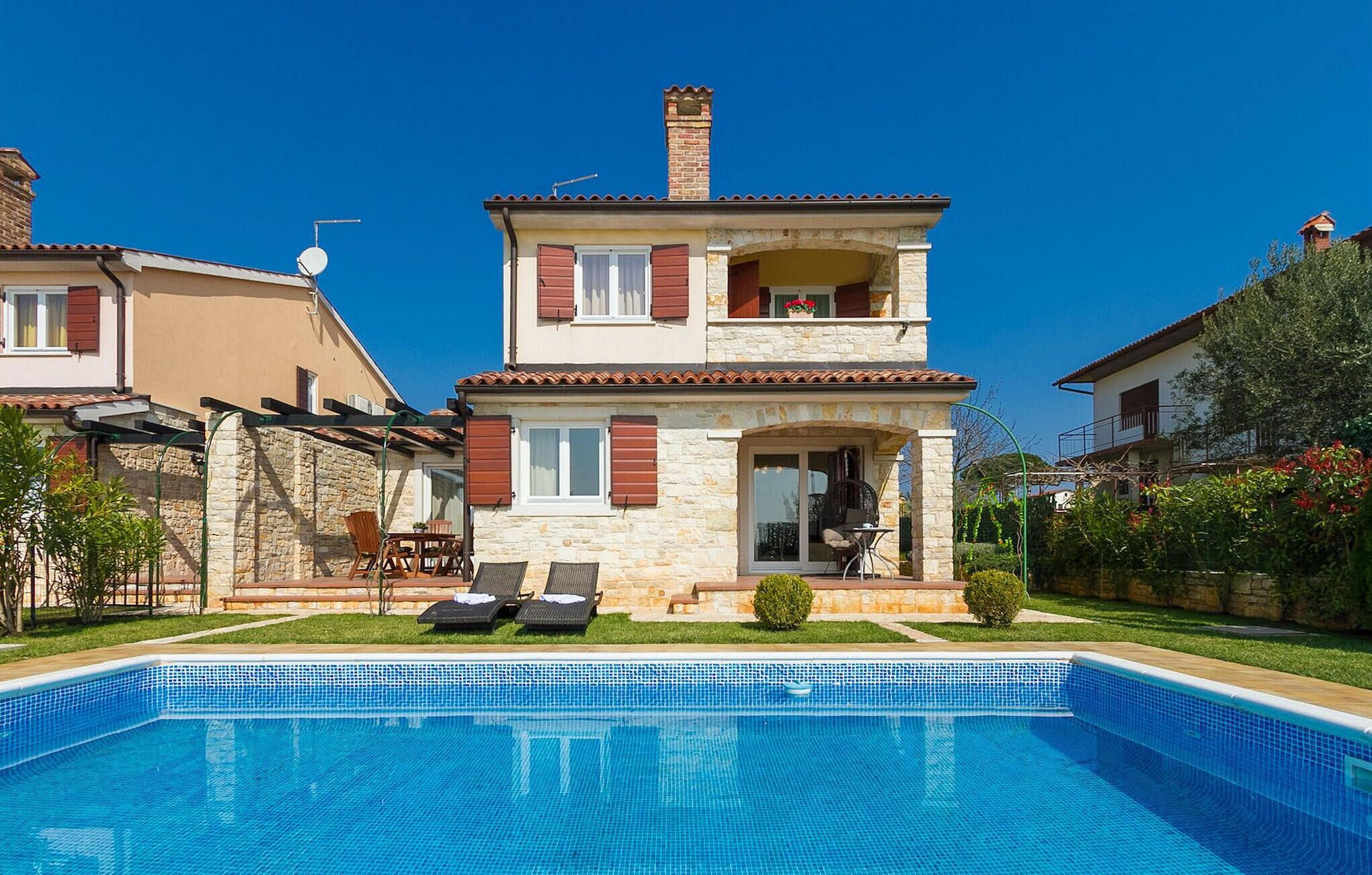 A two-story house with a swimming pool in the foreground.