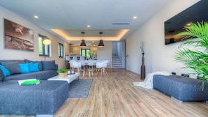 A modern living room with a sofa, dining table, and chairs. There is a staircase leading to another level. - Beautiful home in Porec (Porec)