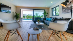 A modern living room with a pool view, a sofa, two chairs, a coffee table, and a lamp. - Beautiful home in Porec (Porec)