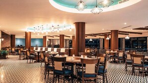 Un restaurante espacioso con techos altos, suelo de diseño geométrico y varias zonas de estar con mesas y sillas.