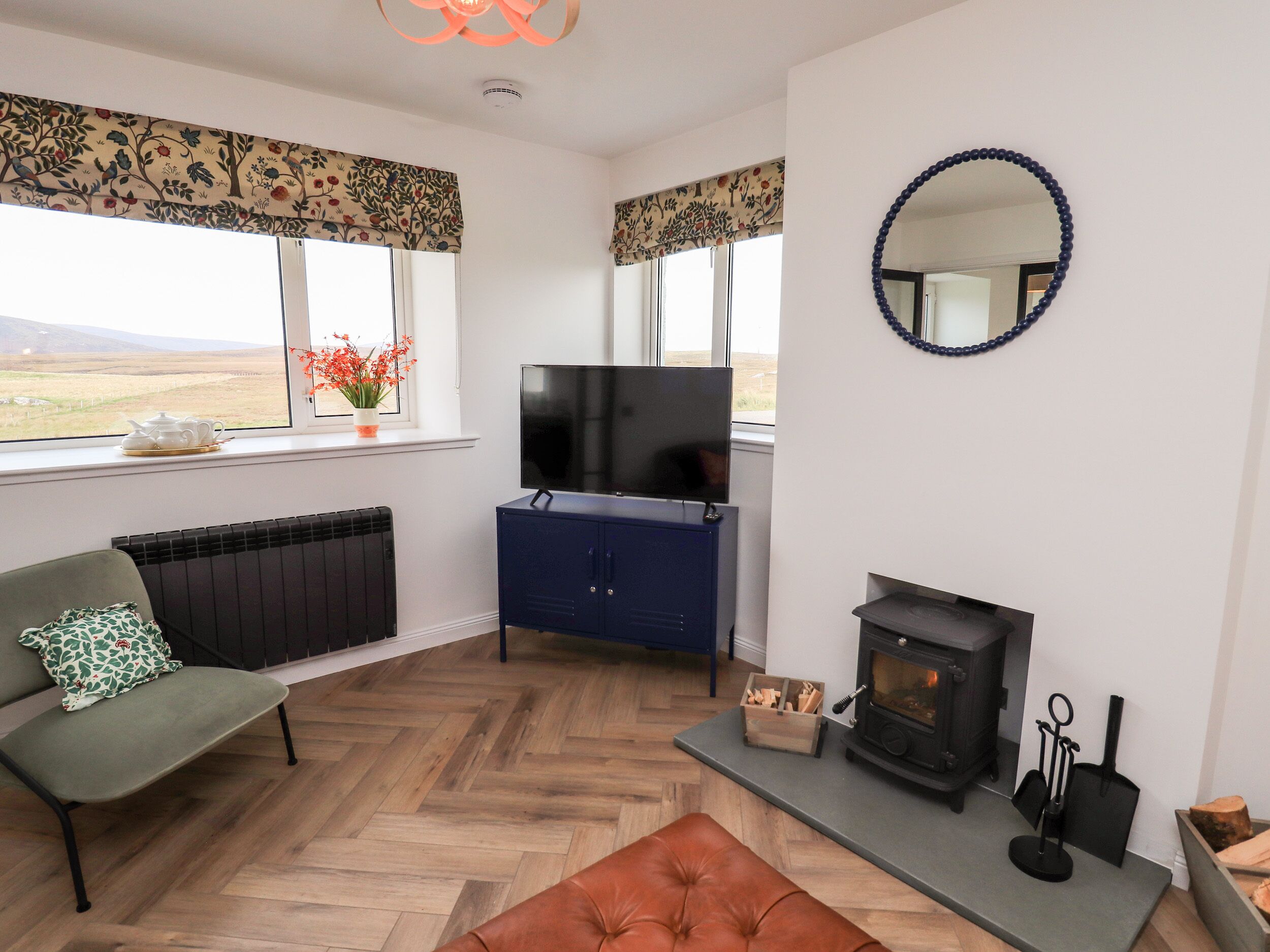 A living room with a sofa, a television, a fireplace, and a view of the outdoors.