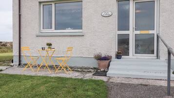 A building with a sign reading "Park Cottage." There are two yellow chairs and a small table outside.