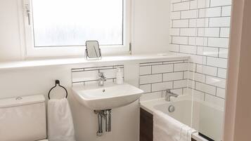 A modern bathroom with a white sink, a bathtub, and a toilet.