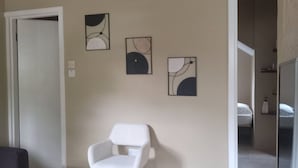 A modern living room with a white armchair, a flat-screen TV, and abstract wall art. - Near Ferry, Airport, Shops, Beaches, Atms, Rodney Bay and Castries - Free Pickup (Castries)
