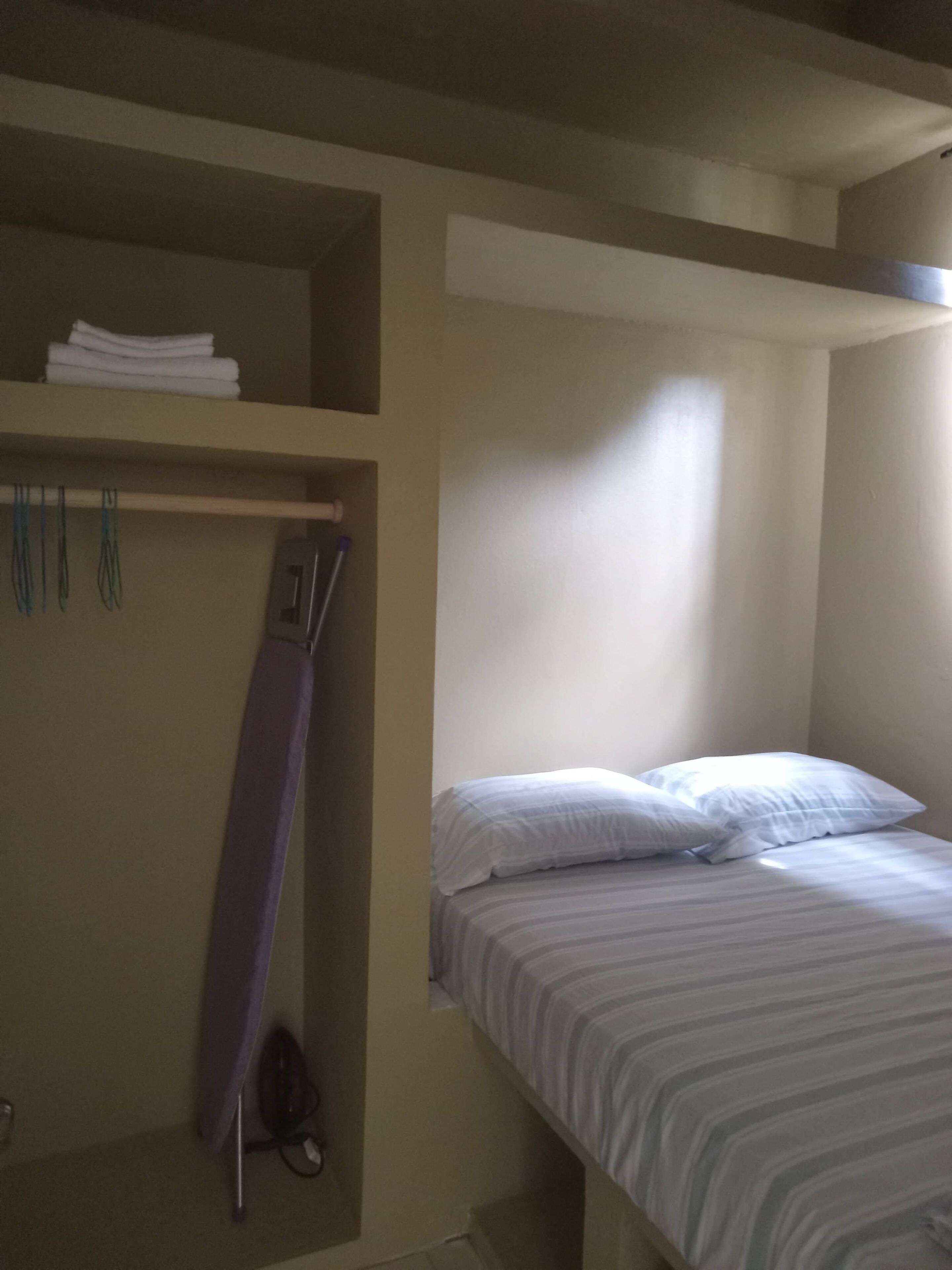 A single bed with white bedding in a room with beige walls.