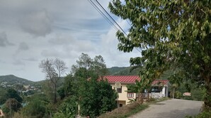 A rural road leading to a building with a red roof, surrounded by greenery and hills. - Near Ferry, Airport, Shops, Beaches, Atms, Rodney Bay and Castries - Free Pickup (Castries)