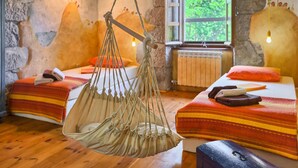 A cozy room with two beds, a hanging chair, and a window with a view of greenery. - Beautiful home in Buzet (Buzet)