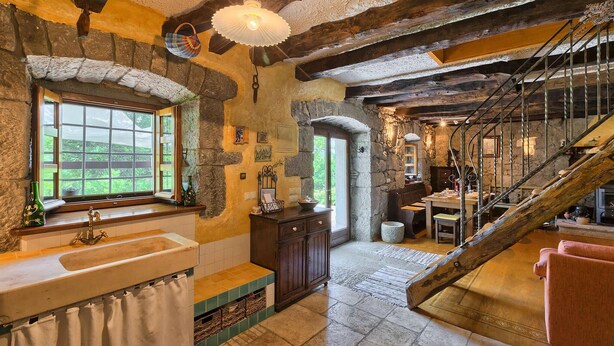 A rustic interior with stone walls, a wooden staircase, and a view through a window. - Beautiful home in Buzet (Buzet)