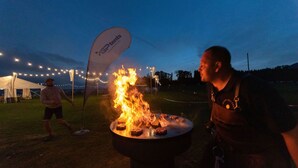 A person grilling meat on an outdoor barbecue.