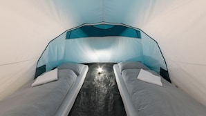 A tent-like room with two beds, a central light source, and a patterned ceiling.