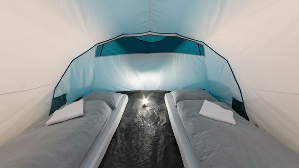A tent-like room with two beds, a central light source, and a patterned ceiling.