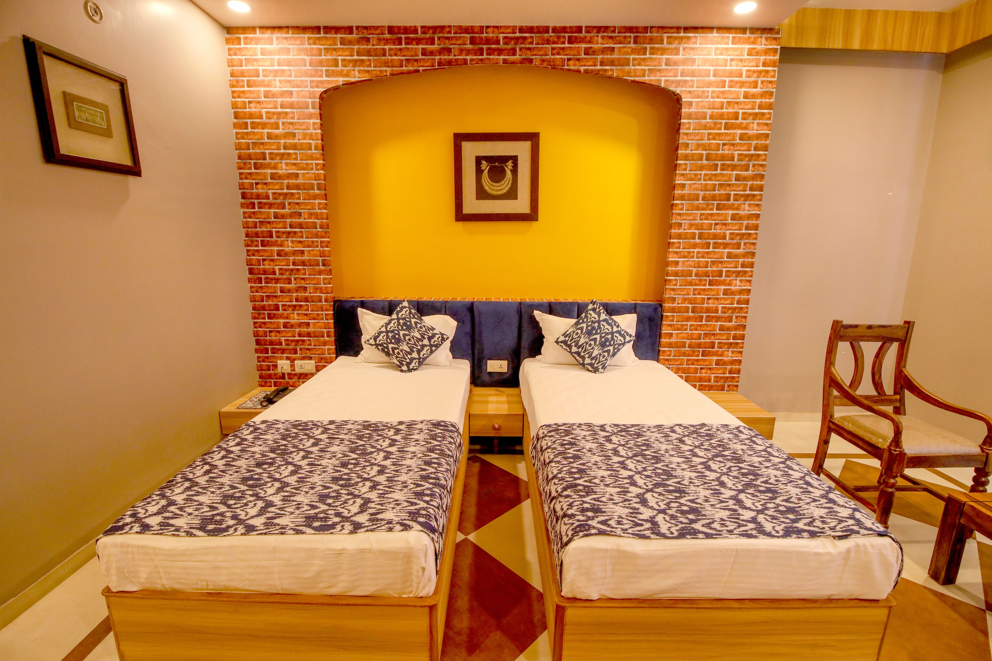 A double room with two beds, a brick accent wall, and a wooden chair.