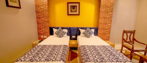 A double room with two beds, a brick accent wall, and a wooden chair.