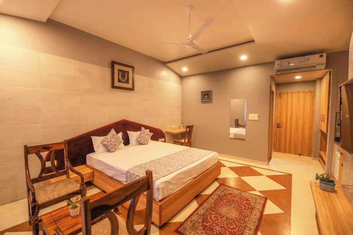 Ein Schlafzimmer mit Bett, Holzmöbeln, Deckenventilator, Fernseher und einer Tür zu einem anderen Raum.
