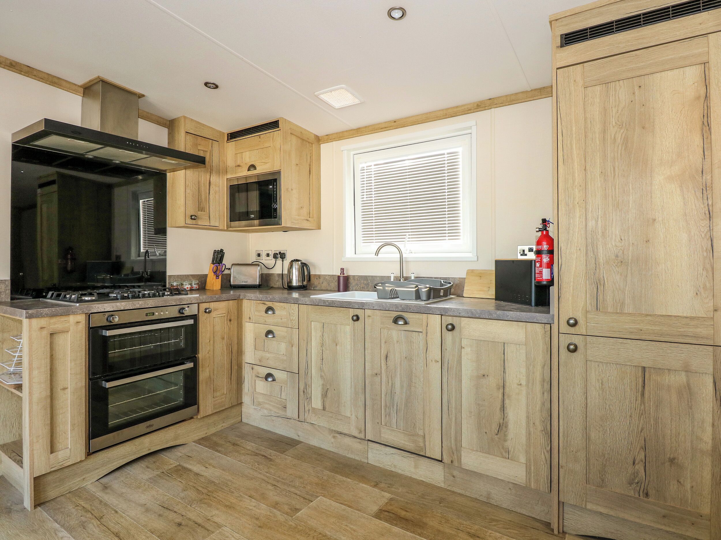 A kitchen with wooden cabinets, a stove, a microwave, and a sink.