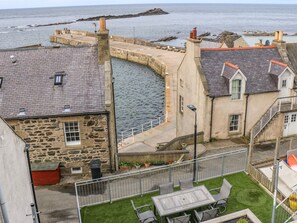 A coastal building with a stone facade, a curved stone wall, and a view of the sea. - Craignure (Banff)