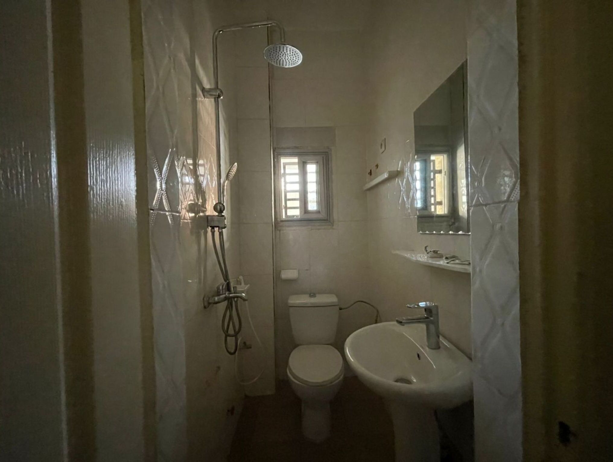 A small, compact bathroom with a shower, toilet, and sink.