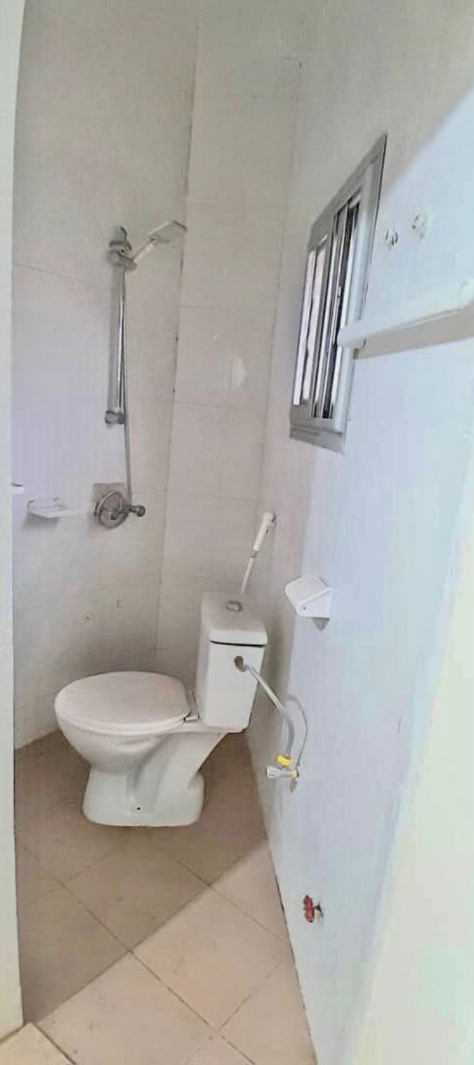 A small, compact bathroom with a toilet, a shower, and a window.