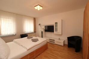 A modern bedroom with a bed, a TV, a small table, and a chair. - Rustic Apartment in Essen (Essen)