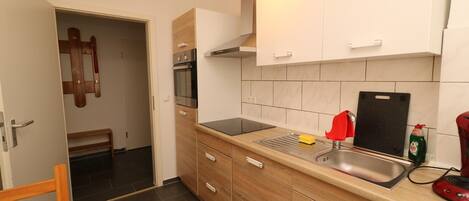 A compact kitchen with a built-in oven, a sink, and wooden cabinets.