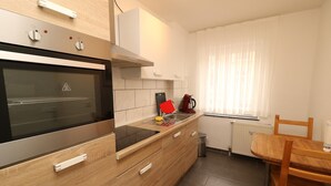 A modern kitchen with a built-in oven, a wooden countertop, and a dining area with a table and chairs. - Rustic Apartment in Essen (Essen)