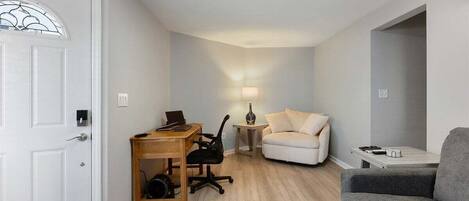 A compact living space with a desk, office chair, sofa, and a grey armchair.