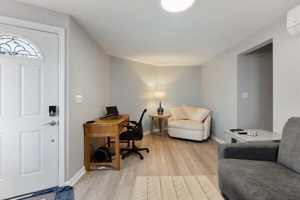 Un espacio habitable compacto con escritorio, silla de oficina, sofá y un sillón gris.