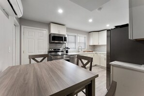 Una cocina moderna con armarios blancos, un refrigerador de acero inoxidable y una mesa de comedor.