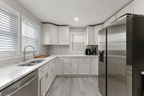 Uma cozinha moderna com armários brancos, eletrodomésticos de aço inoxidável e painel de azulejos.