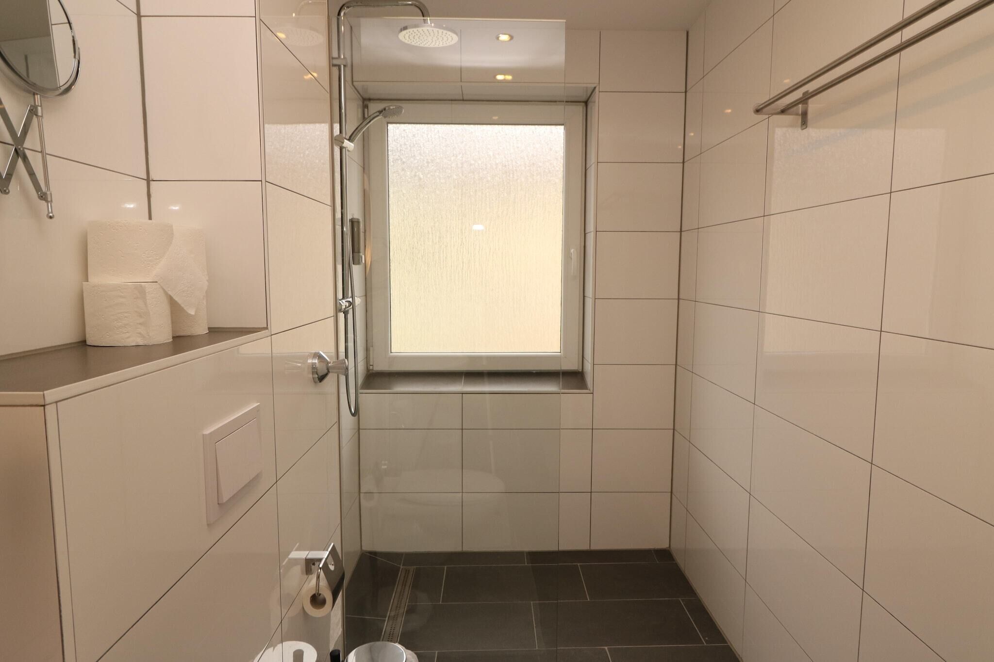 Une petite salle de bain moderne, équipée d’une douche, de toilettes et d’une fenêtre.