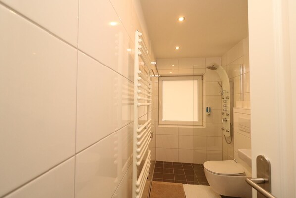 A modern bathroom with a toilet, shower, and a window. - Apartment in Essen for two with Private Terrace (Essen)