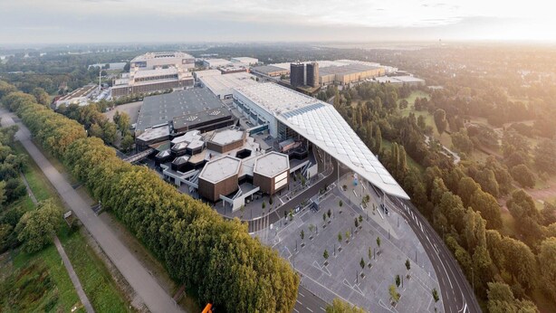 Vue aérienne d’un complexe immobilier moderne composé de plusieurs bâtiments, entouré d’arbres et d’espaces ouverts.