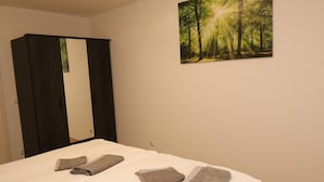 Ein Hotelzimmer mit einem Bett, zwei Handtüchern, einem Spiegel und einem Wandbild mit Waldmotiv.