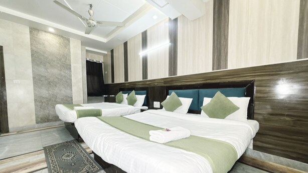 A hotel room with two beds, a ceiling fan, and a view of the hallway. - Hotel Alpine By The Golden Taj Group (Agra)
