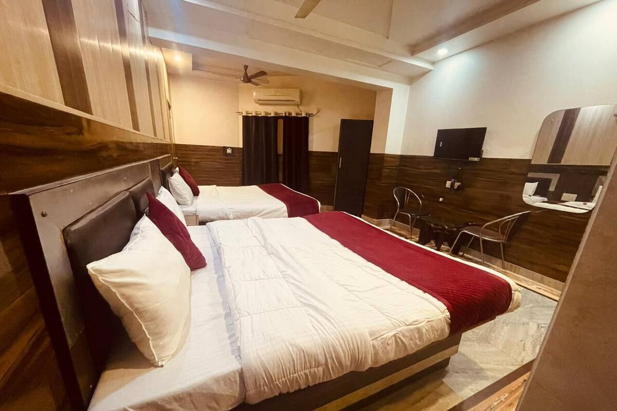 Une chambre d’hôtel avec deux lits, un téléviseur à écran plat, un ventilateur de plafond et une petite table avec des chaises.