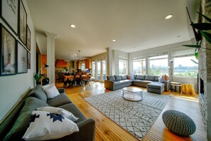 A spacious living room with a large sectional sofa, a coffee table, and a dining area with chairs and a table.