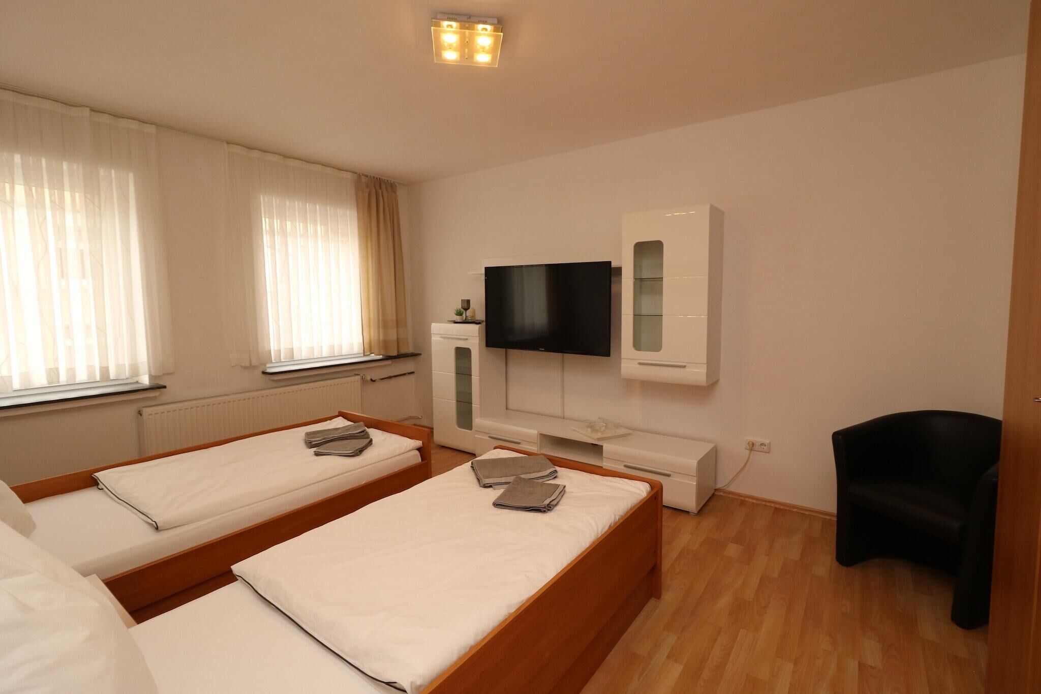 Een hotelkamer met twee eenpersoonsbedden, een flatscreen-tv, een klein bureau en een stoel.