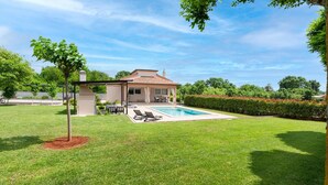 Une maison avec une piscine, un patio couvert et une pelouse bien entretenue.