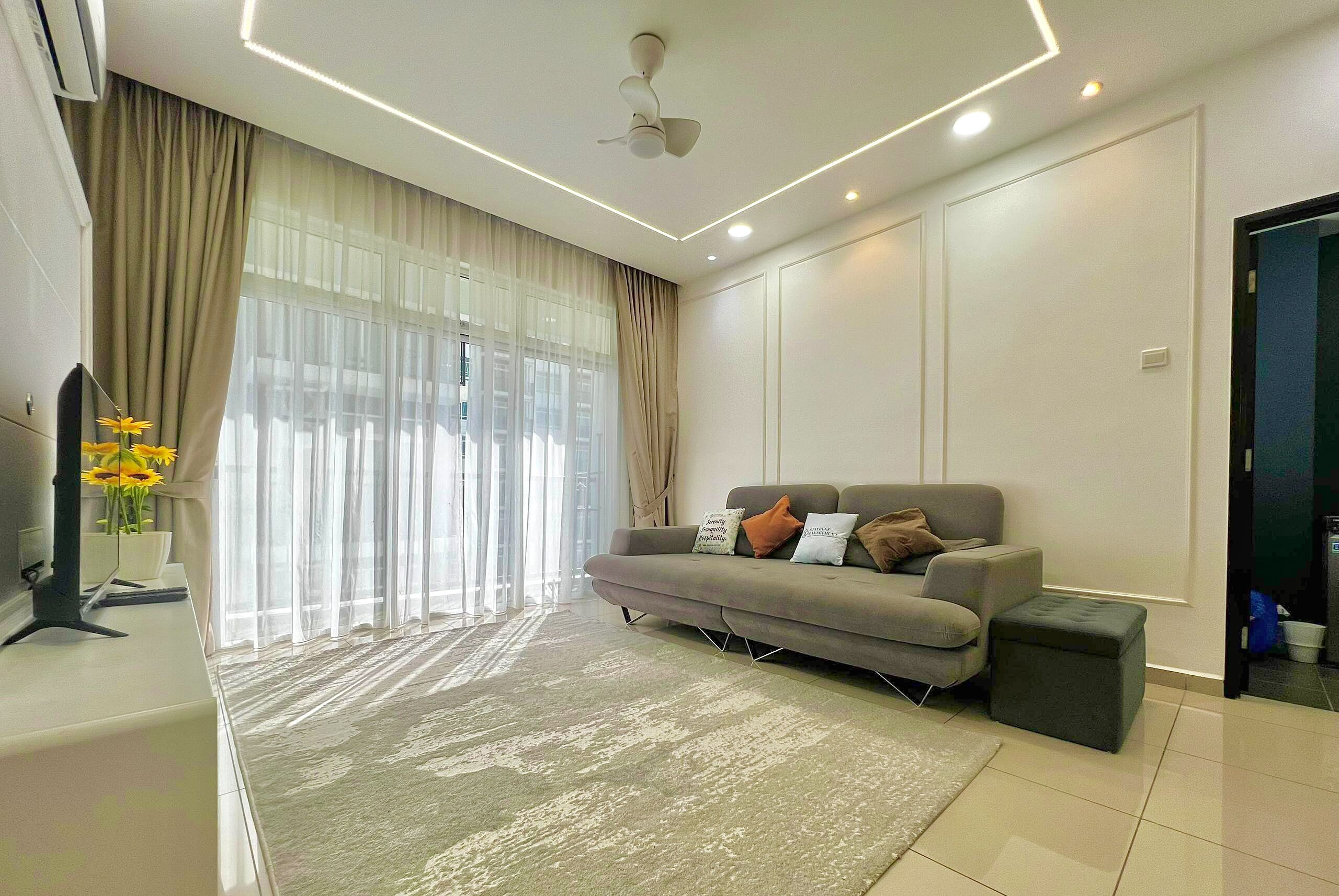 A modern living room with a grey sofa, beige curtains, and a large window.