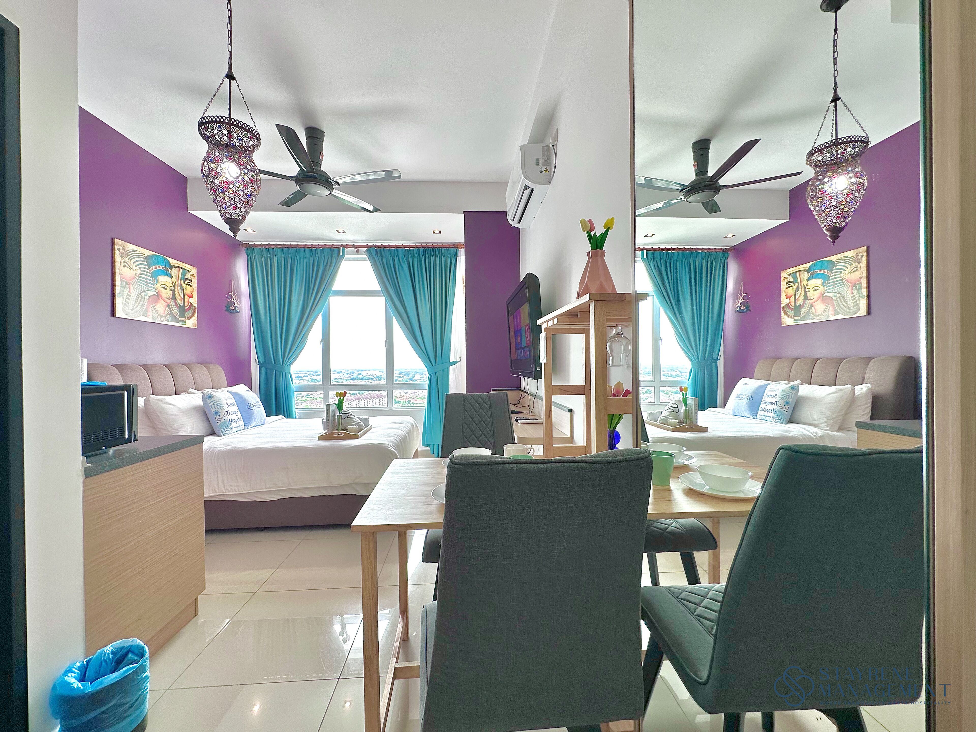 Habitación de hotel con dos camas, una mesa de comedor, sillas, televisor y vistas de la ciudad.
