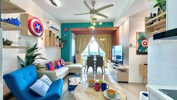 A modern living room with a blue sofa, a dining table with colorful mugs, and a TV.