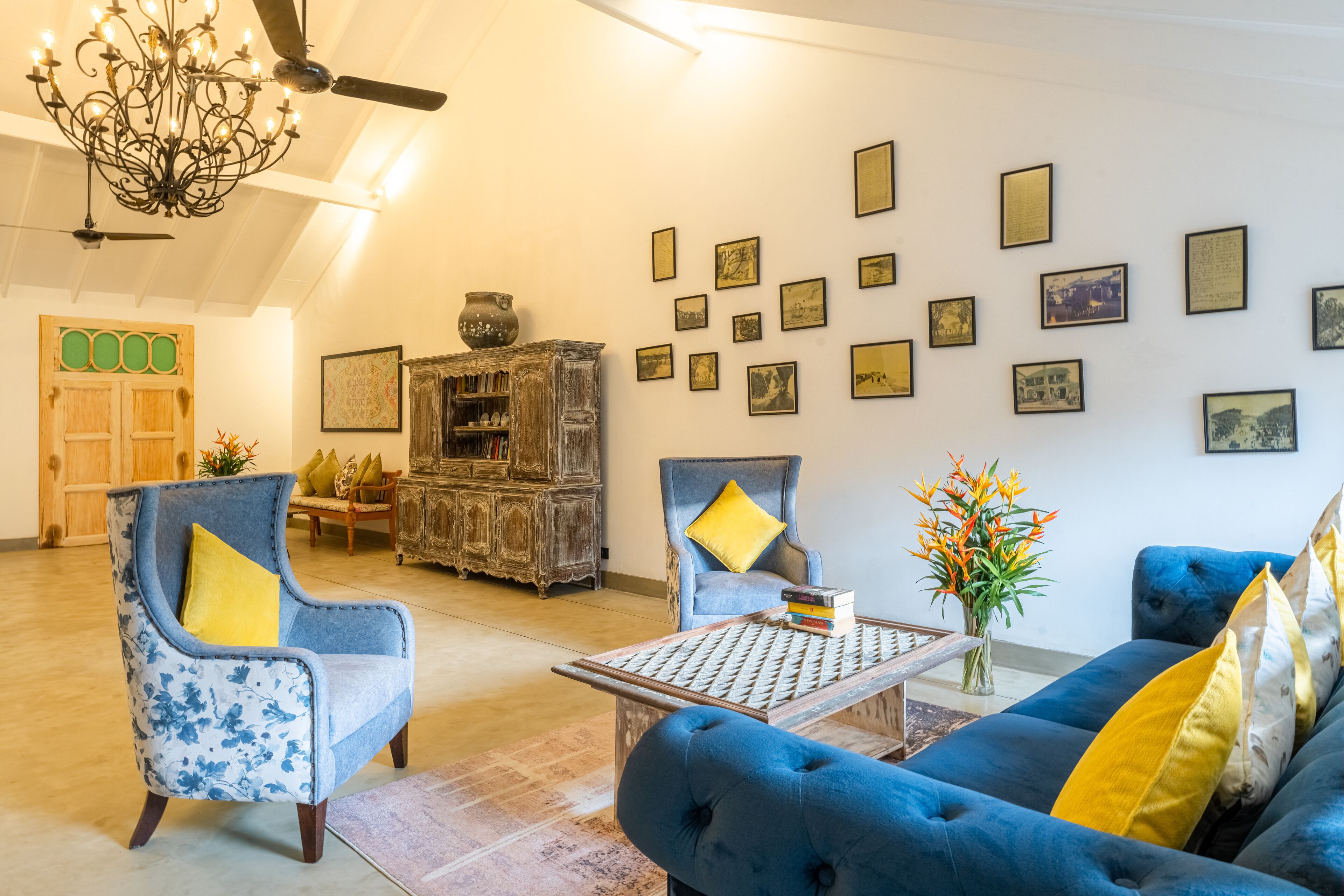 A living room with a blue sofa, two armchairs, a coffee table, and a chandelier.