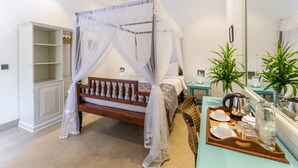 A bedroom with a canopy bed, a wardrobe, a bedside table with a tray of breakfast items, and a mirror. - The Fort House (Galle)
