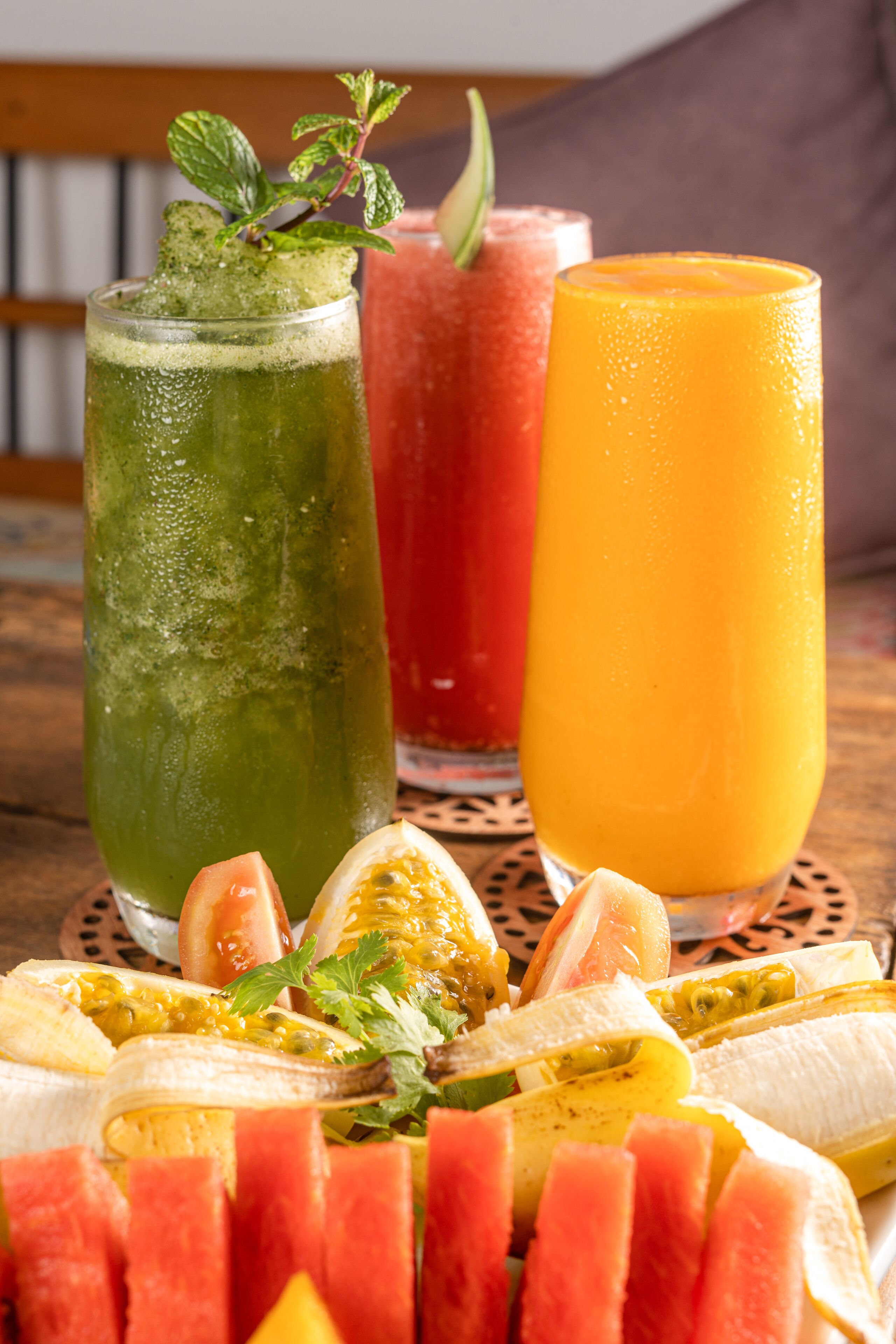 A table with a variety of fruits and two tall glasses of juice.
