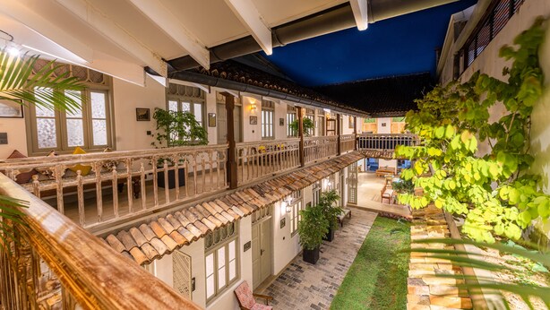A courtyard with a covered walkway, potted plants, and outdoor seating. - The Fort House (Galle)