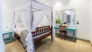 Un dormitorio con cama de dosel, un escritorio con silla y un espejo.