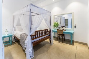 Un dormitorio con cama de dosel, un escritorio con silla y un espejo.