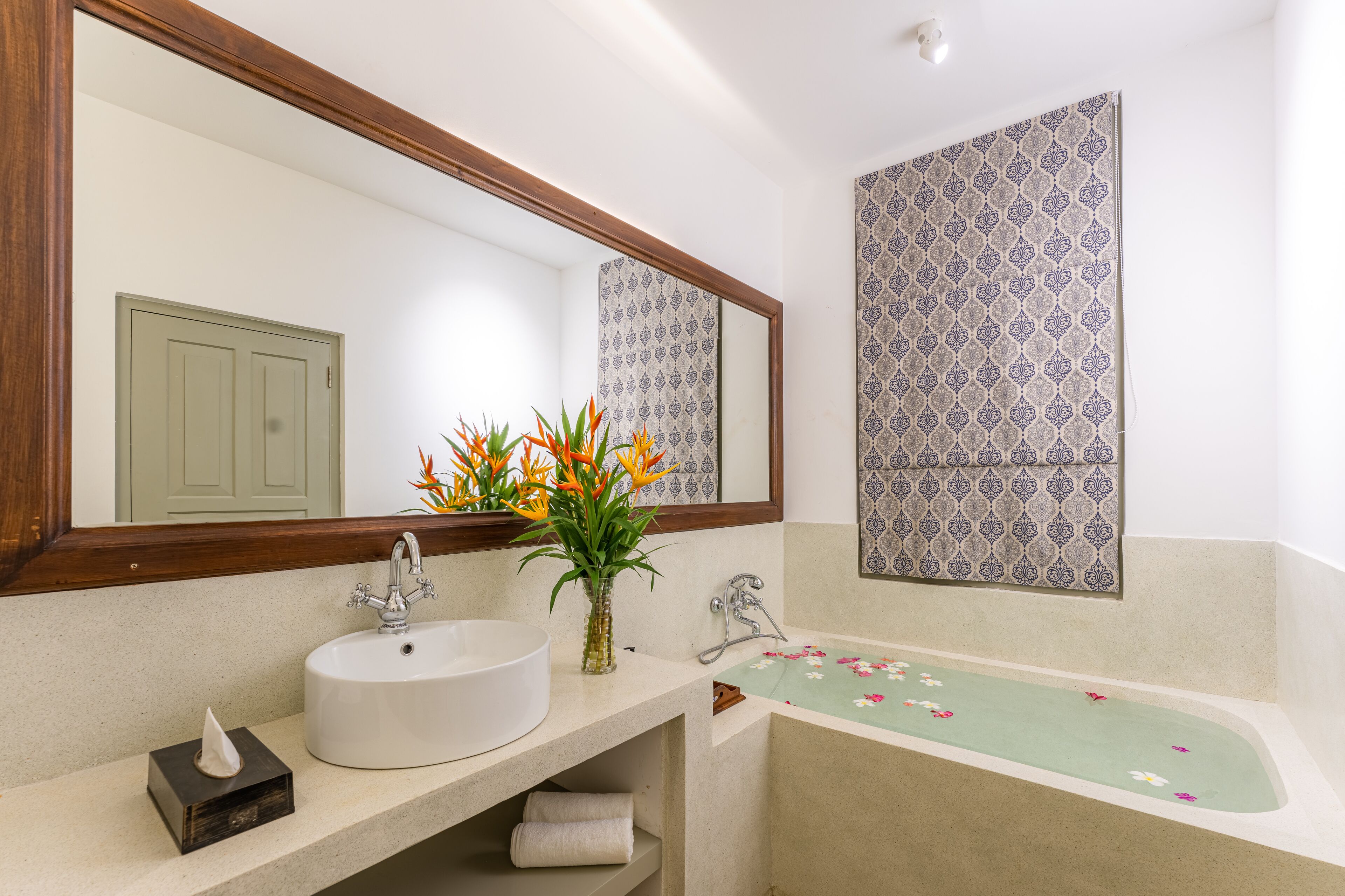 A bathroom with a sink, mirror, and bathtub.